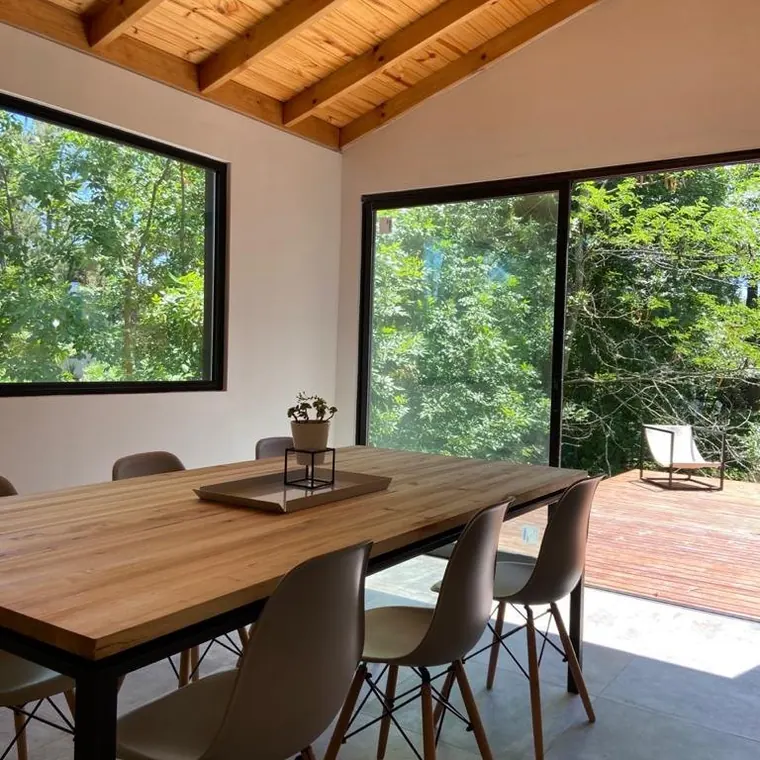 El comedor bajo el techo de madera a la vista, abierto al deck