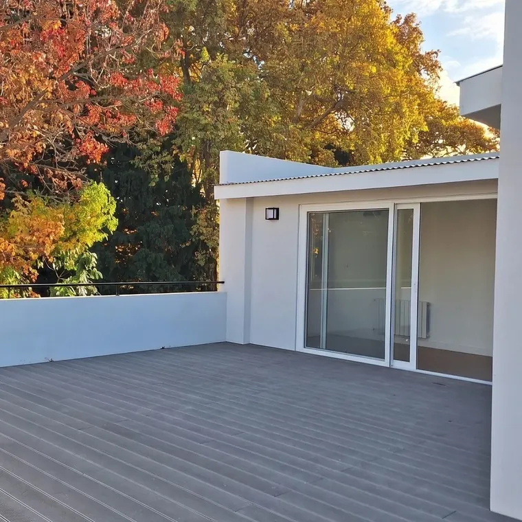 Terraza sumada en planta alta sobre una casa en Olivos, Vicente López: deck gris y ventanal corredizo al nuevo ambiente